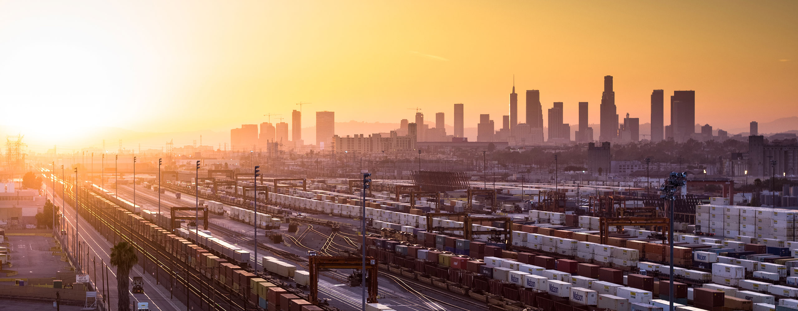 Intermodal railyard filled with containers beside train tracks in front of city landscape