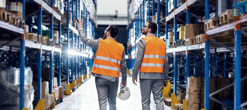 Two warehousing professionals walking through short and long-term storage racks